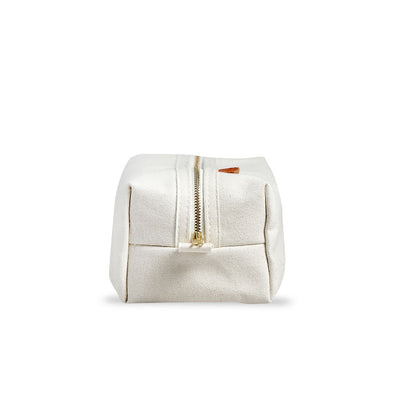 End view of Dopp kit made from sturdy off-white canvas with metal zipper and leather detail. Classic small travel and toiletry bag.