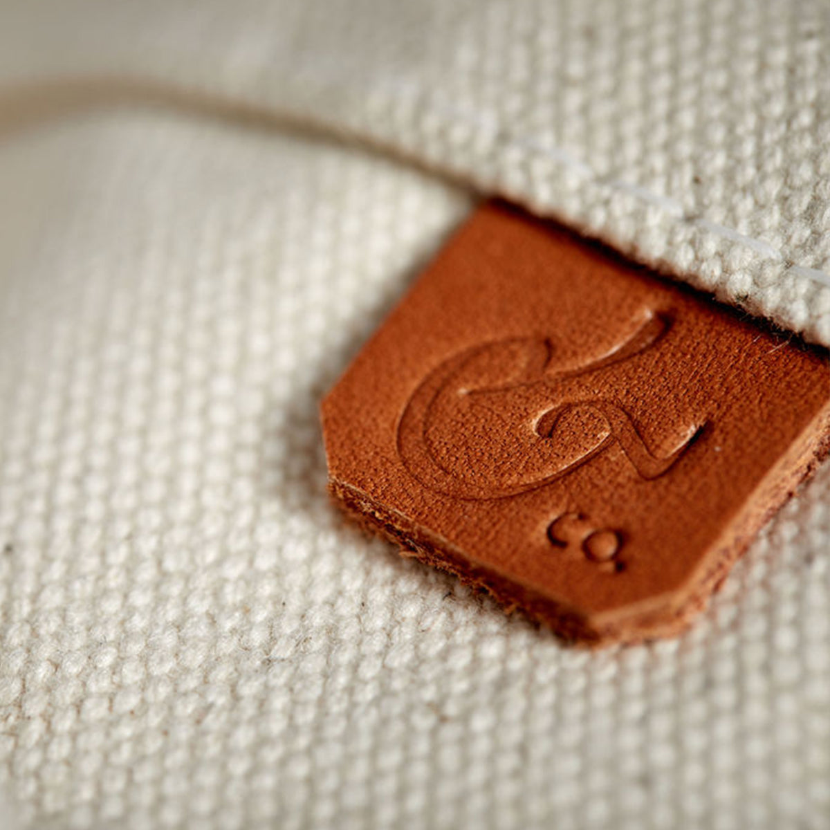 Close-up of handcrafted, heirloom-quality bucket bag. Durable off-white canvas, leather detail and outer pockets.