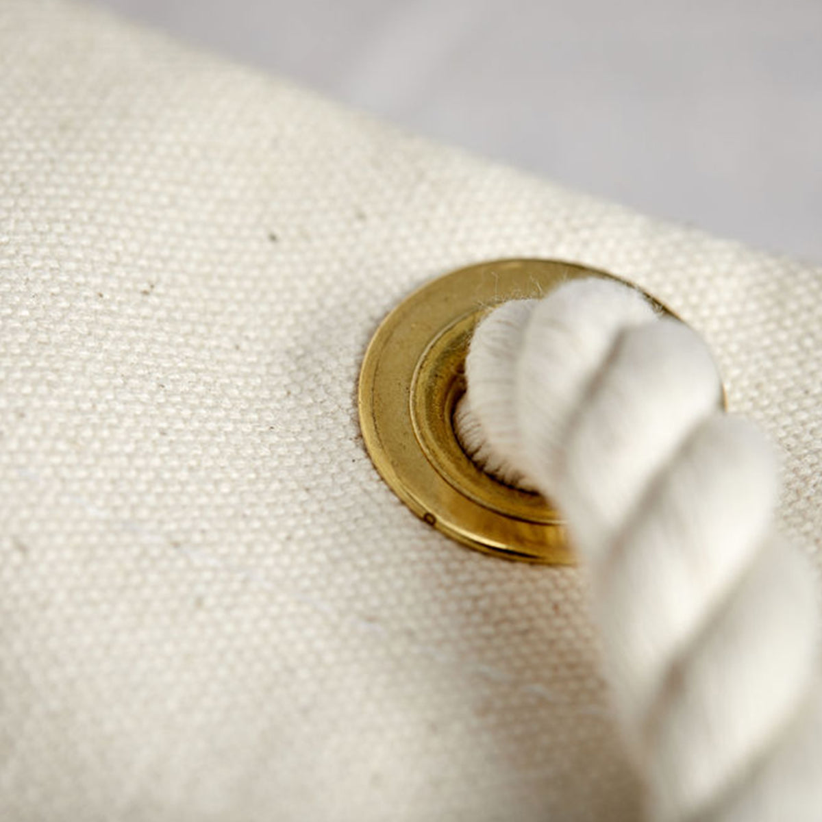 Close-up of cotton rope and brass grommet in durable canvas bucket bag. Handcrafted, heirloom-quality craftsmanship.