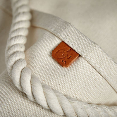 Close-up of handcrafted, heirloom-quality bucket bag. Durable off-white canvas, cotton rope, leather detail and outer pockets.