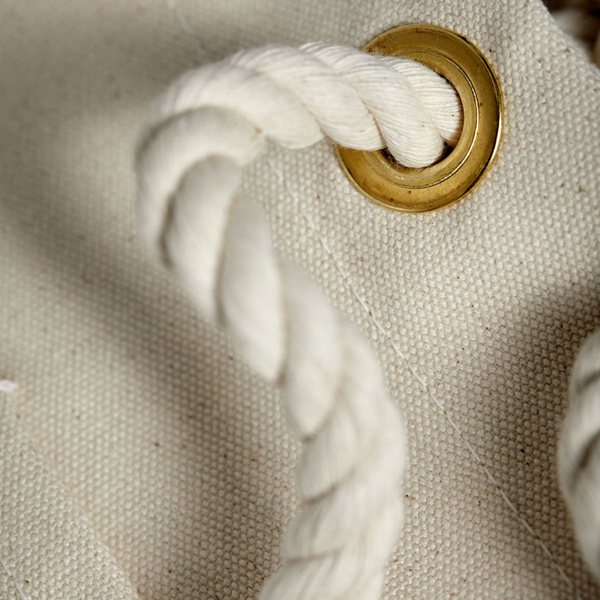 Close-up detail of minimalist, maritime-inspired canvas tote bag. Thick cotton rope and brass hardware.
