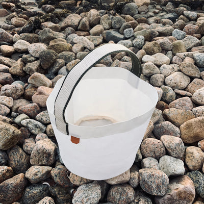 Durable, ultralight white sailcloth bucket bag made from repurposed materials on a beach in Midcoast Maine